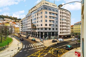 A multi-story hotel with a curved facade, located at a city intersection with a tram line and pedestrian crossings. - Contemporary Comfort in Historic Lisbon (Lisbon)