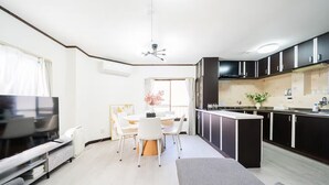Un salon moderne doté d’un téléviseur à écran plat, d’un canapé et d’un coin repas avec une table et des chaises.