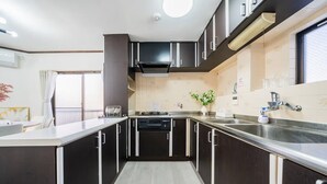 Une cuisine moderne avec des meubles de couleur sombre, un plan de travail en acier inoxydable, un four encastré et un évier.