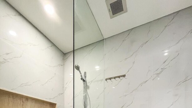 A modern bathroom with a glass shower enclosure, a toilet, and a sink.