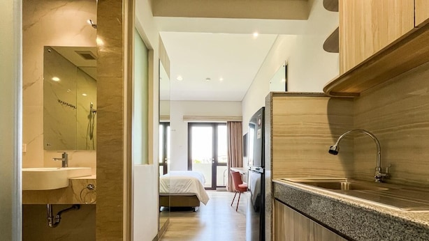 Una moderna camera d'albergo con angolo cottura, bagno, un letto e vista sull'esterno.