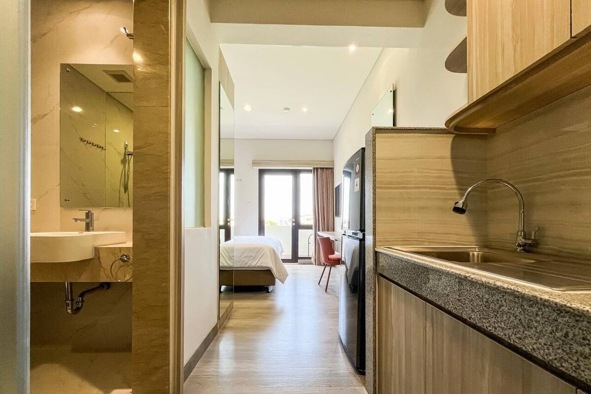 Una habitación de hotel moderna con kitchenette, baño, cama y vistas al exterior.