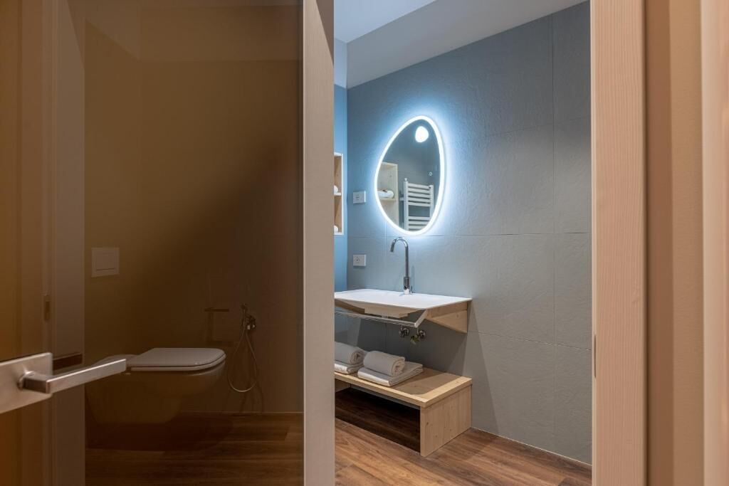 A modern bathroom with a toilet, shower, and vanity with a mirror.
