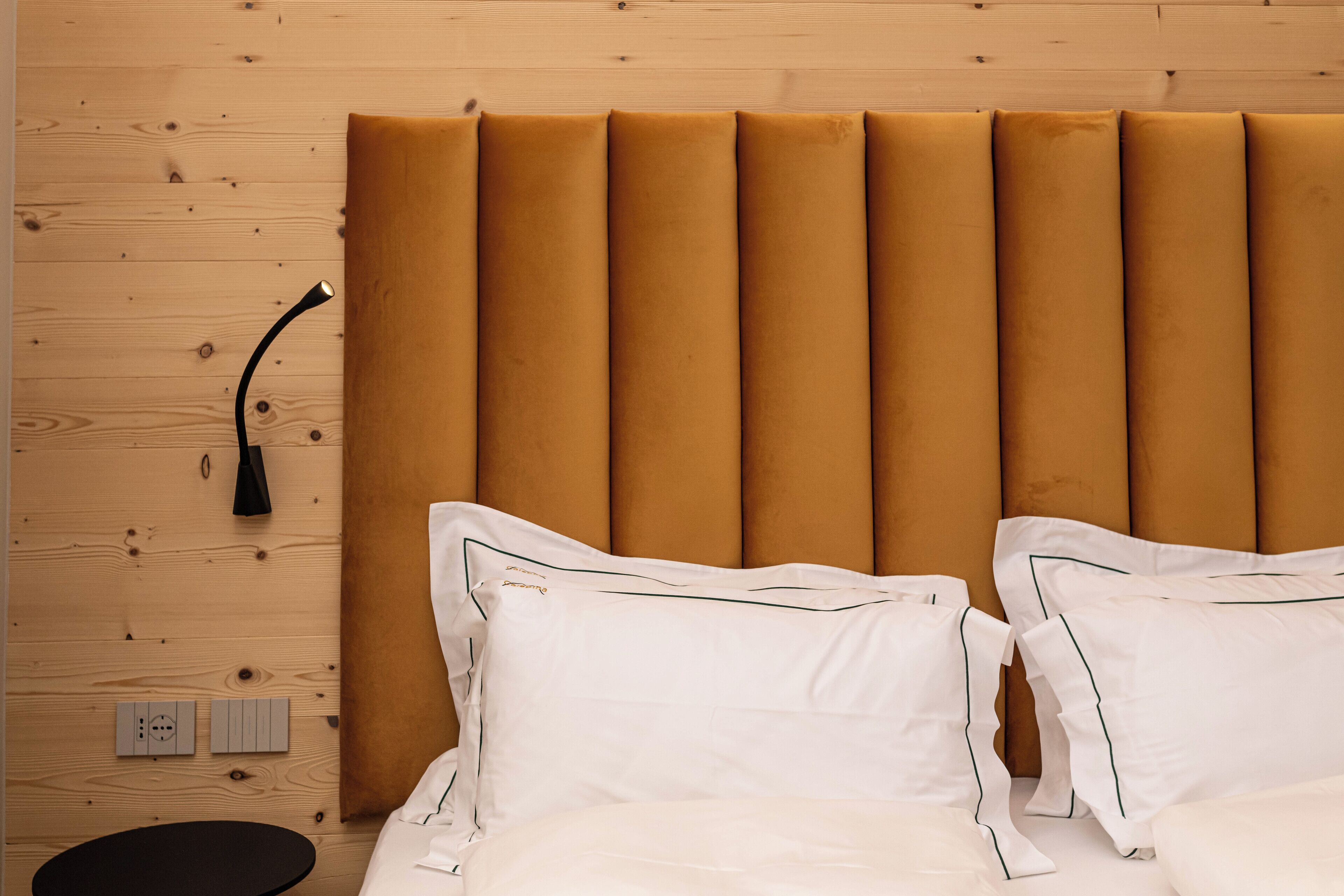 A neatly made bed with white linens and a headboard with vertical panels.