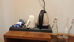 A kitchenette with a kettle, coffee maker, and bottles on a wooden counter. - Casa Bella Resort Thekkady (Kumily)