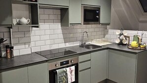 A modern kitchen with grey cabinets, a black countertop, a built-in oven, and a microwave. - Stylish 2-Bed Apartment in the Heart of Windsor – Walk to Windsor Castle (Windsor)