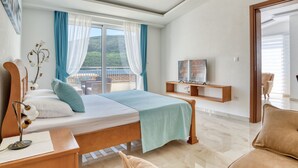 A modern hotel room with a bed, a desk, a chair, a TV, and a balcony with a view of the sea. - Ljubica Superior 3-Zimmer-Apartment mit Meerblick by Interhome (Herceg Novi)