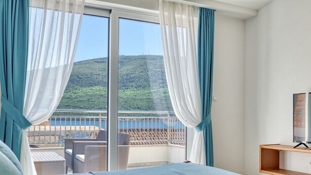 A hotel room with a bed, a TV, and a balcony with a view of a hillside. - Ljubica Superior 3-Zimmer-Apartment mit Meerblick by Interhome (Herceg Novi)