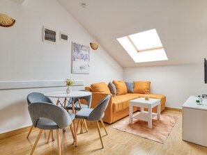 Une pièce agréable et bien éclairée, comprenant un coin repas, un canapé et une petite table.