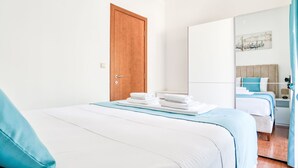 Habitació d'hotel amb un llit, una tauleta de nit, un mirall i una porta.