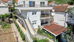 Ein zweistöckiges Gebäude mit Balkon, Treppe und Garten.
