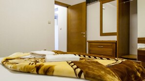 Ein Hotelzimmer mit einem Bett, einem Holzschrank, einem Spiegel und einem an der Wand befestigten Fernseher.