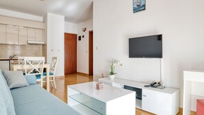 A modern living room with a sofa, coffee table, TV, and a kitchen area in the background. - Wohnung "Premier" mit Meerblick by Interhome (Herceg Novi)
