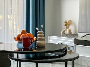 A modern interior with a glass table displaying oranges, a vase, and a red mug. A Louis Vuitton bag is visible on a white cabinet. - Qoople Elite 4 Elize 8 neue Wohnung im Stadtzentrum by Interhome (Alanya)