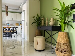 A modern kitchen with white cabinets, a dining table with chairs, and a green accent wall. There are two large woven vases on a black console table. - Qoople Elite 4 Elize 29 neue Wohnung im Stadtzen by Interhome (Alanya)