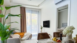A modern hotel room with a bed, a dining area with a marble table, a TV, and a large window with curtains. - Qoople Aria-07 neue Wohnung im Stadtzentrum by Interhome (Alanya)