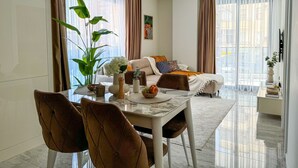 A modern living room with a dining area, large windows, and a view of the city. - Qoople Aria-07 neue Wohnung im Stadtzentrum by Interhome (Alanya)