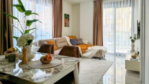 A modern living room with a sofa, dining table, and a large window with curtains. - Qoople Aria-07 neue Wohnung im Stadtzentrum by Interhome (Alanya)
