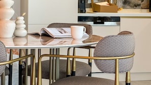 Een moderne keuken met een marmeren spatwand, een eettafel met stoelen en een koffieapparaat.