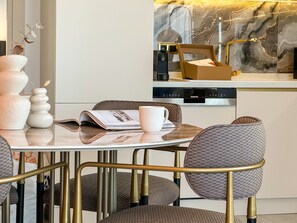 Eine moderne Küche mit Marmor-Spritzschutz, einem Esstisch mit Stühlen und einer Kaffeemaschine.