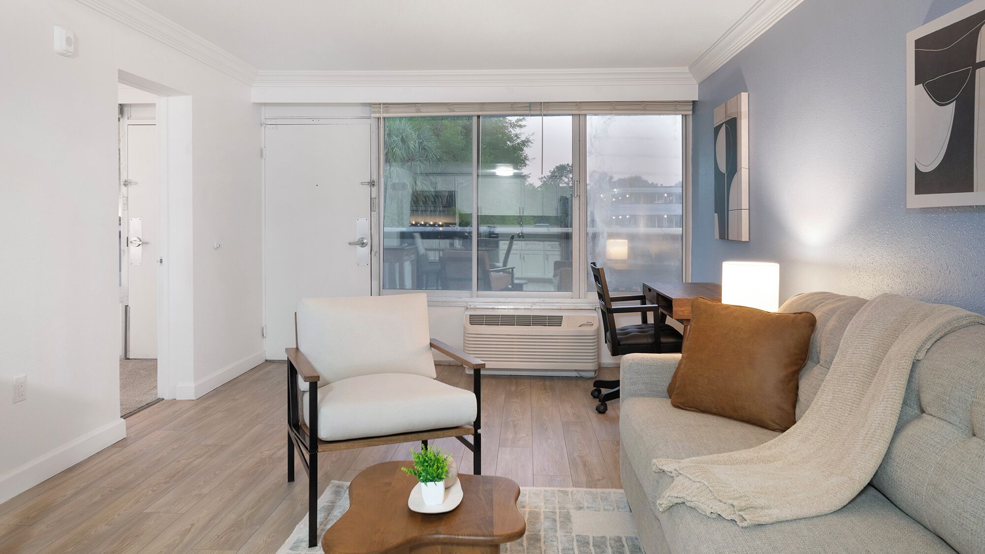 A modern living room with a sofa, armchair, and a dining table with chairs.