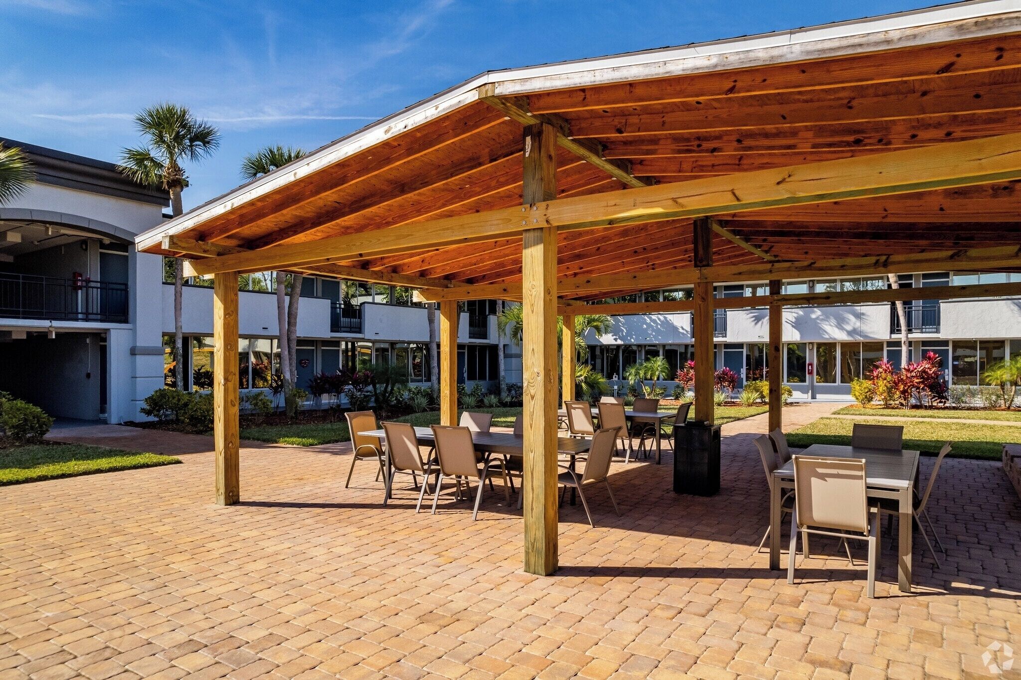 An outdoor patio with wooden pergola, brick flooring, and outdoor seating.