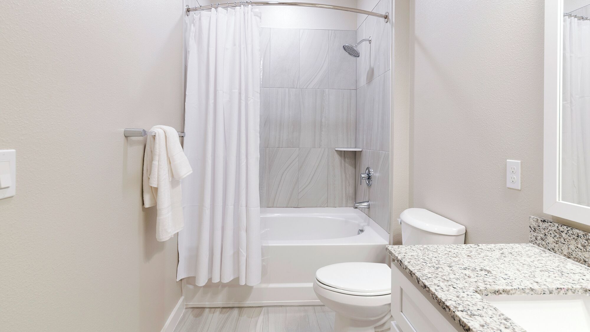 A modern bathroom with a shower, toilet, and sink.