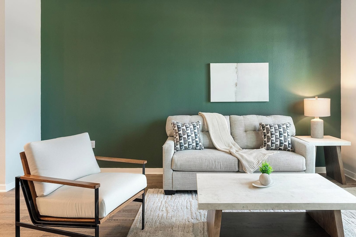 A living room with a sofa, a chair, a coffee table, and a lamp.