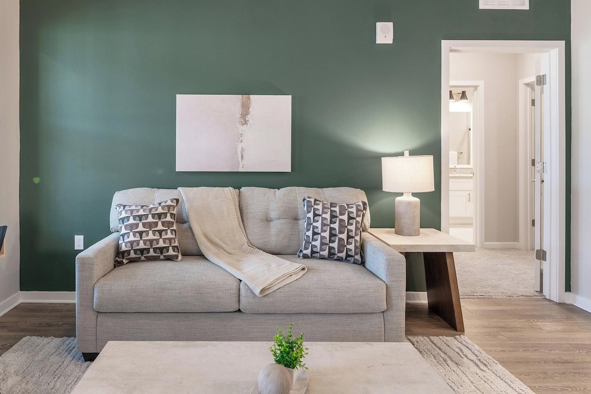 A living room with a sofa, a coffee table, a lamp, and a painting on the wall.