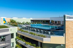 A rooftop pool with lounge chairs and a modern building with a green roof and brick walls. - Landing Apartments Springdale - Austin (Austin)