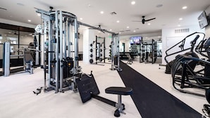 Ein modernes Fitnessstudio mit verschiedenen Trainingsgeräten, darunter Kraftgeräte, ein Laufband und eine Bank.
