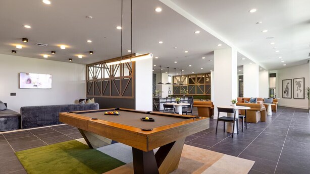Ein Billardtisch in einer modernen Lounge-Ecke mit einer Couch und einer Essecke.