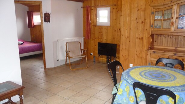 A wooden interior with a dining table, chairs, a bed, a television, and a window. - In a quiet arboretum 3 km from Bergerac town center in Périgord (Bergerac)