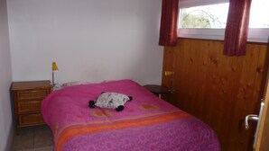 A bedroom with a bed, a nightstand, a lamp, and a wooden door. - In a quiet arboretum 3 km from Bergerac town center in Périgord (Bergerac)