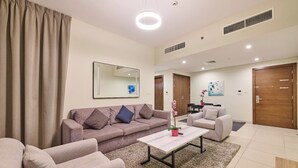 A modern living room with a sofa, armchairs, a coffee table, and a rug. There is a dining table with chairs in the background. - Grand Stay Holidays Homes Rental Satwa (Dubai)