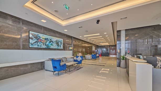 A modern lobby with a reception desk, seating area, and a large abstract painting on the wall. - Grand Stay Holidays Homes Rental Satwa (Dubai)