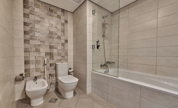 A bathroom with two toilets, a bidet, a bathtub, and a shower. - Grand Stay Holidays Homes Rental Satwa (Dubai)