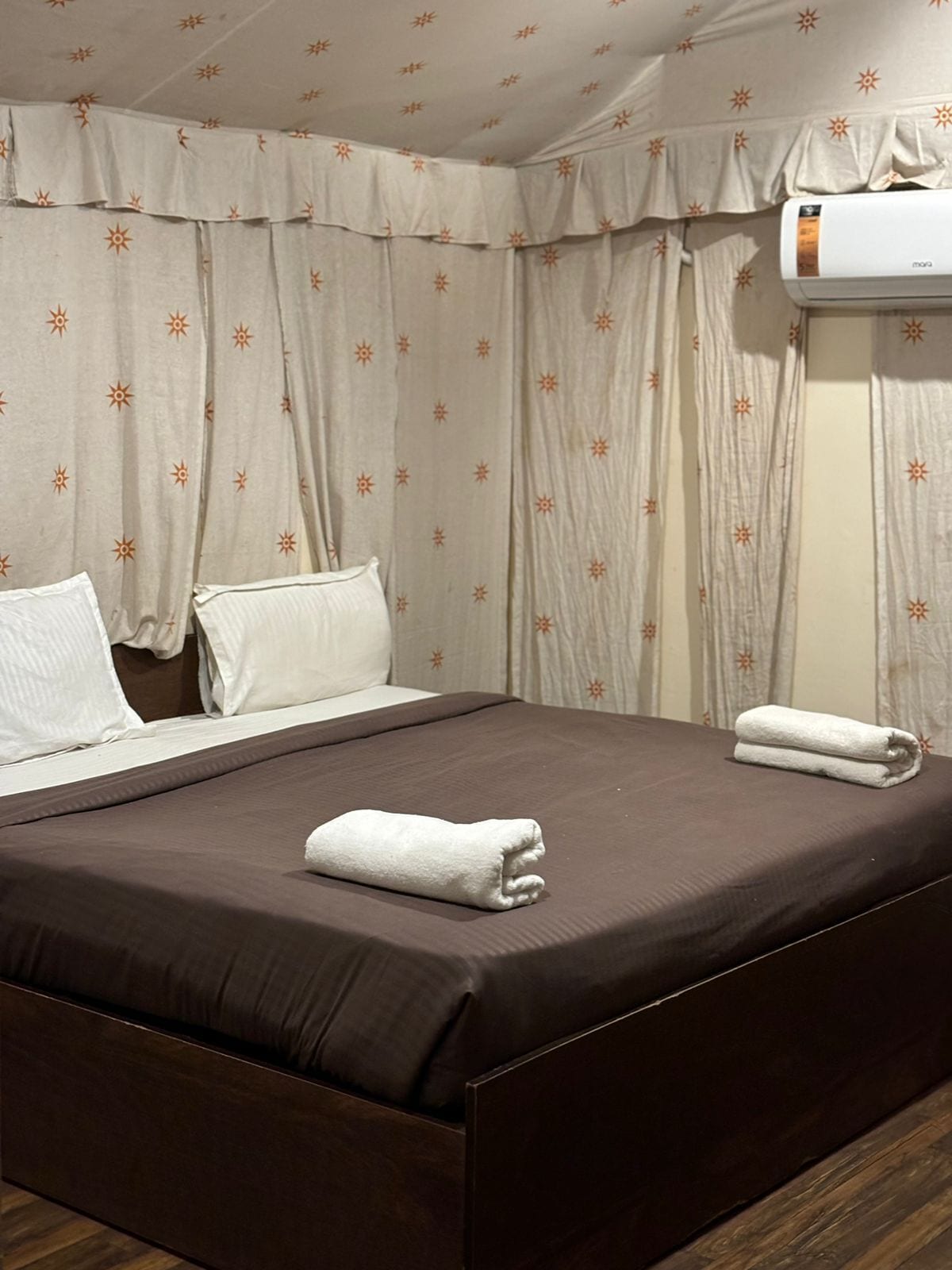 Una habitación de hotel con cama, almohadas, cortinas y un equipo de aire acondicionado.