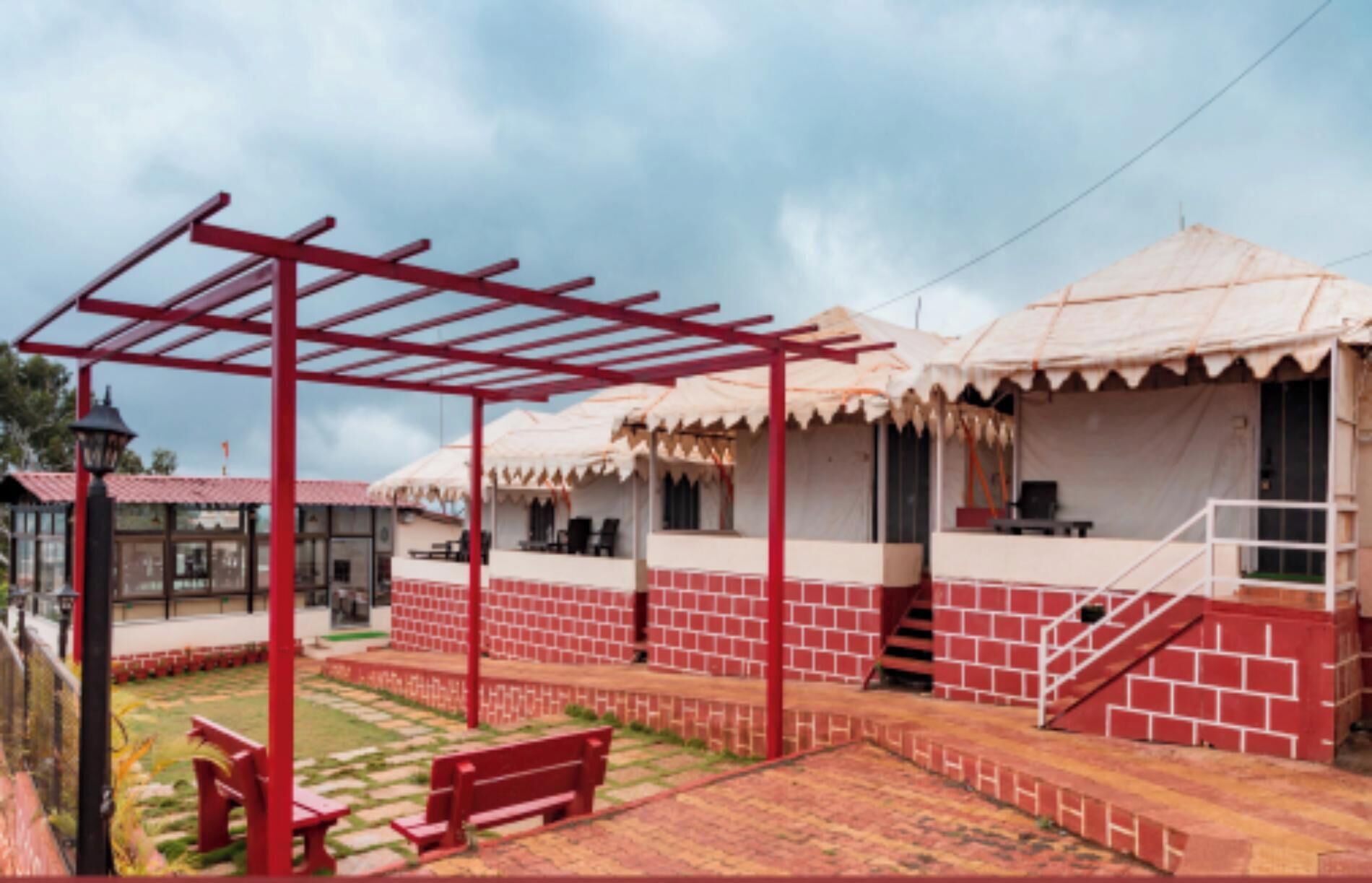 A courtyard with red brick buildings, a pergola, and a covered seating area.