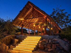 A thatched-roof pavilion with a staircase leading up to it, surrounded by rocks and vegetation. - Enchanted Escapes Yala (Palatupana)