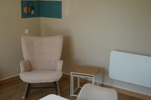 Ein Zimmer mit einem großen weißen Sofa, einem kleinen Holztisch und einem rosa Stuhl.
