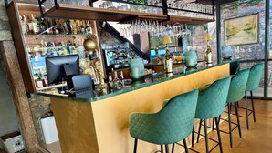 A bar area with a counter, bar stools, and a variety of bottles and glasses. - Baia d'oro (Gargnano)