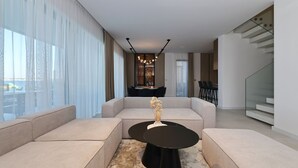 A modern living room with a sofa set, a round black coffee table, and a dining area in the background. - The Palms Resort Villa Waterfront with Pool (Tkon)