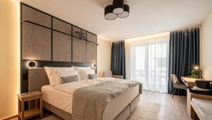A modern hotel room with a large bed, a desk, and a chair. - Malom és Kacsa Boutique Hotel (Tata)