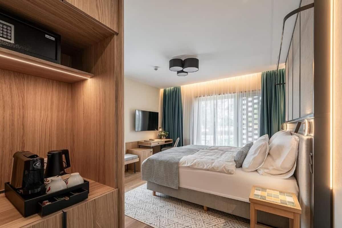 A modern hotel room with a bed, bedside table, and a coffee station.