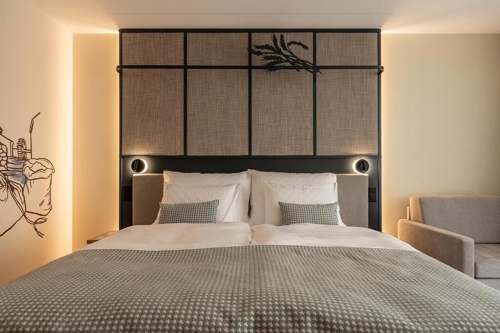 A neatly made bed with a patterned bedspread, a headboard with a textured panel, and bedside lamps.