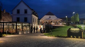 A cobblestone street leading to a building with a large glass facade and a sign reading "Matom & Kacsa." - Malom és Kacsa Boutique Hotel (Tata)