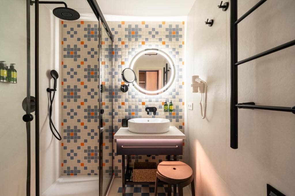 Ein modernes Badezimmer mit Dusche, Waschbecken mit Spiegel und einer kleinen Hocker.