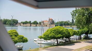 A riverside view with boats docked, a castle-like building, and well-maintained greenery.