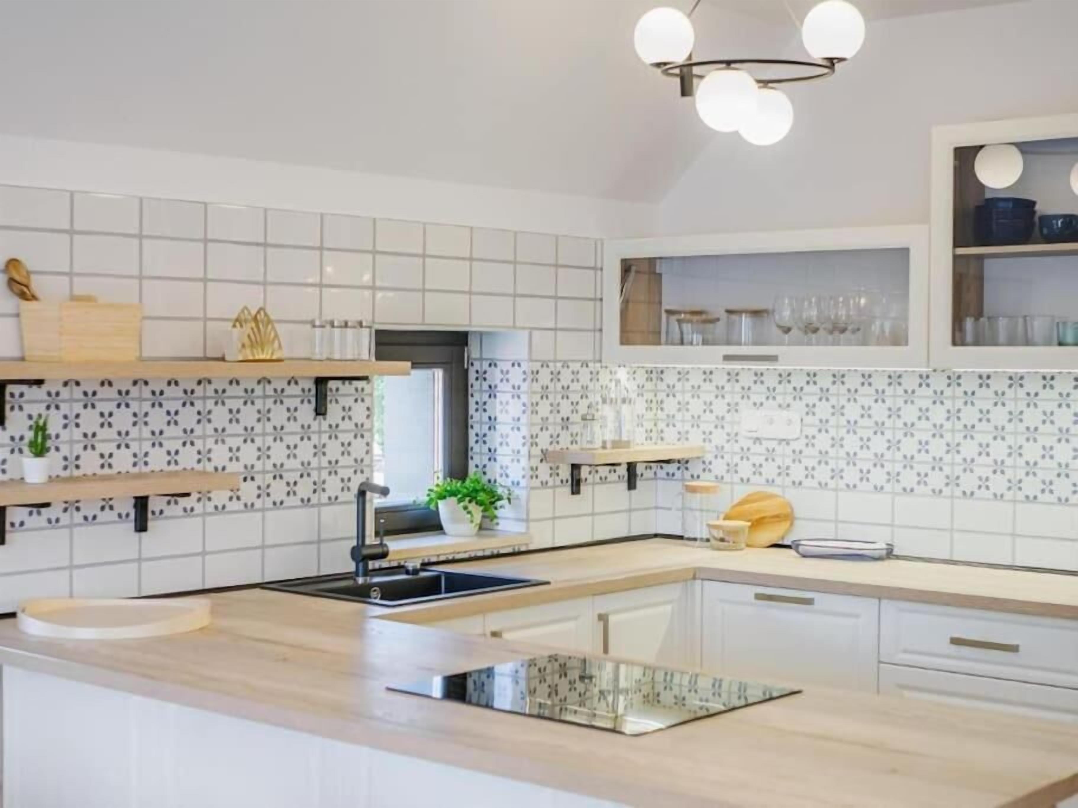 Una cucina moderna con piastrelle bianche, un piano di lavoro in legno ed scaffali a incasso.